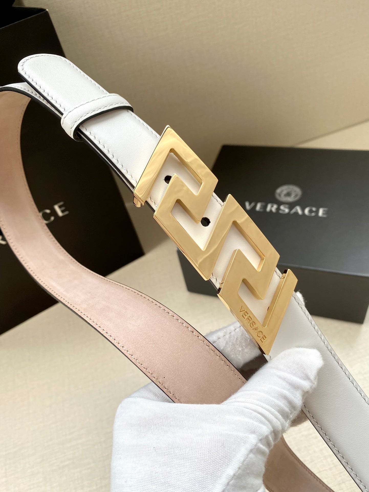 White leather belt with large gold-tone FF buckle, close-up angle