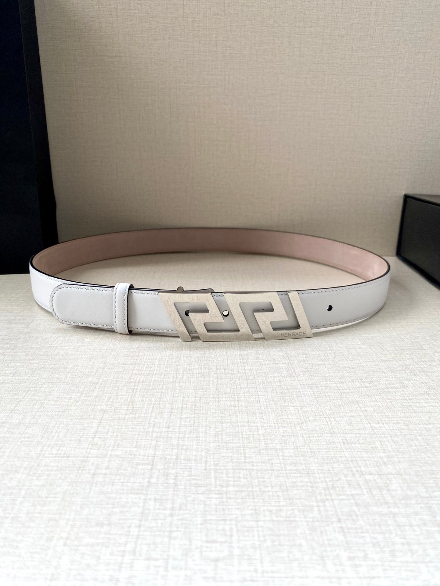 White belt with light pink underside and gold-tone FF buckle, curved view