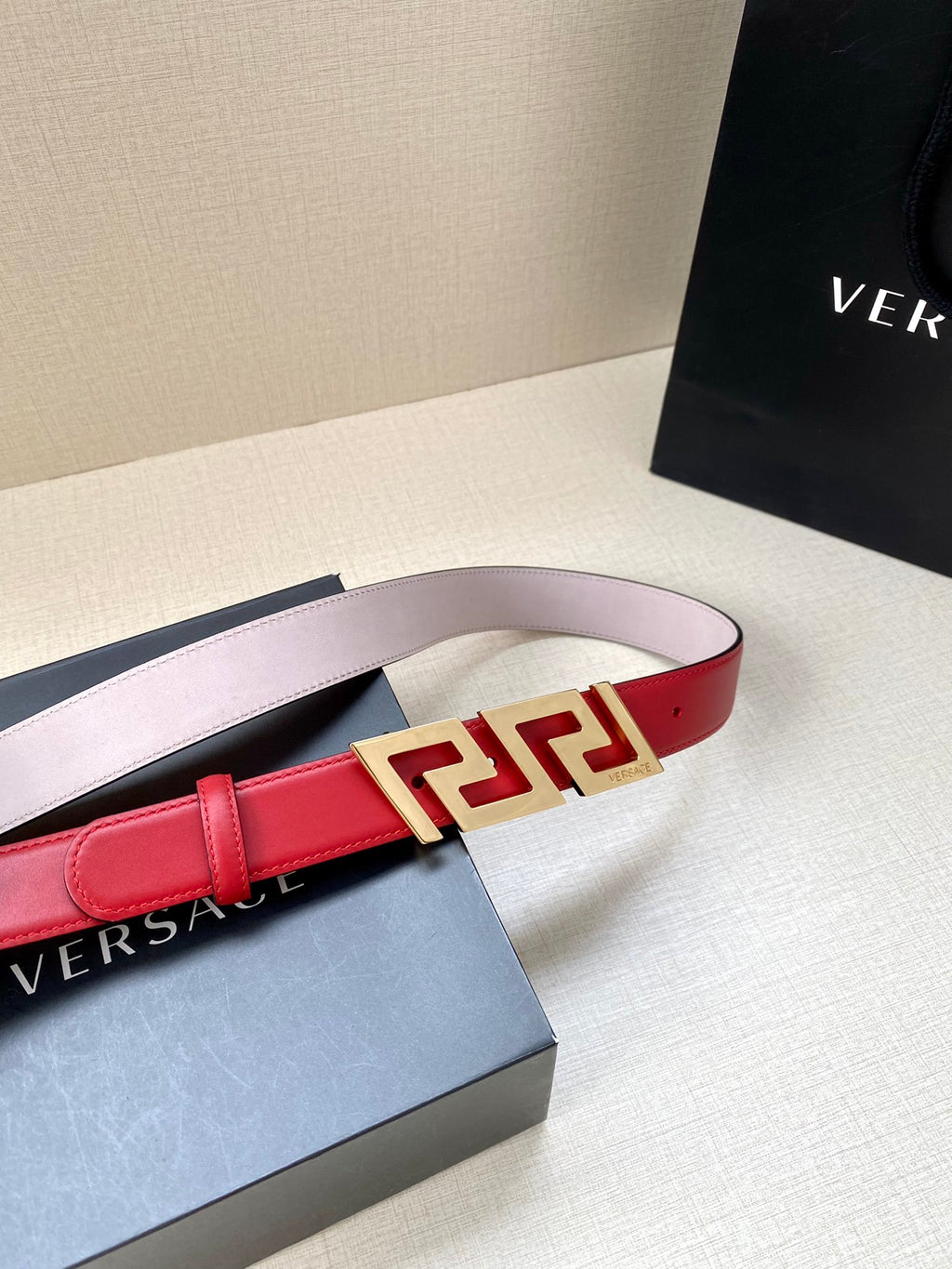 Versace belt with pale pink outer strap, red center panel, and gold Greek-key buckle