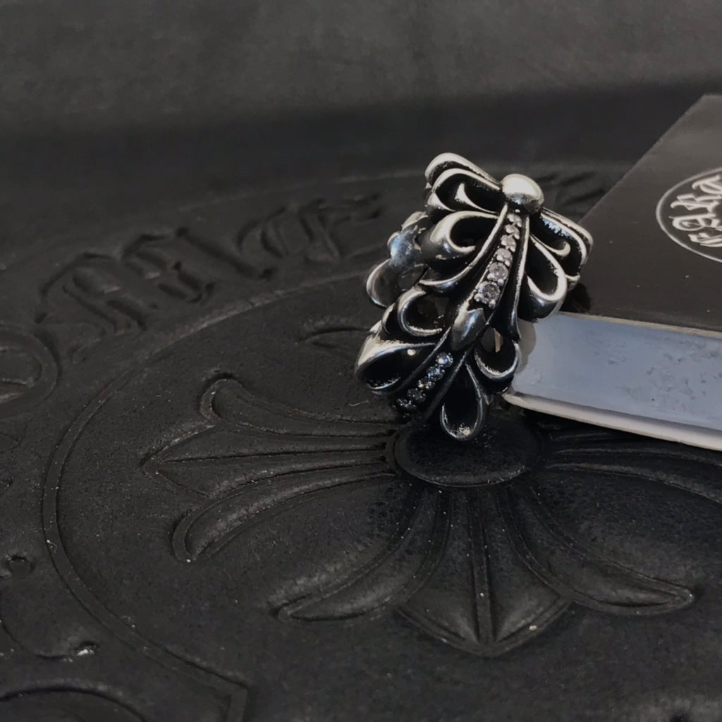 Silver-tone floral filigree ring with rhinestone accents, side view.