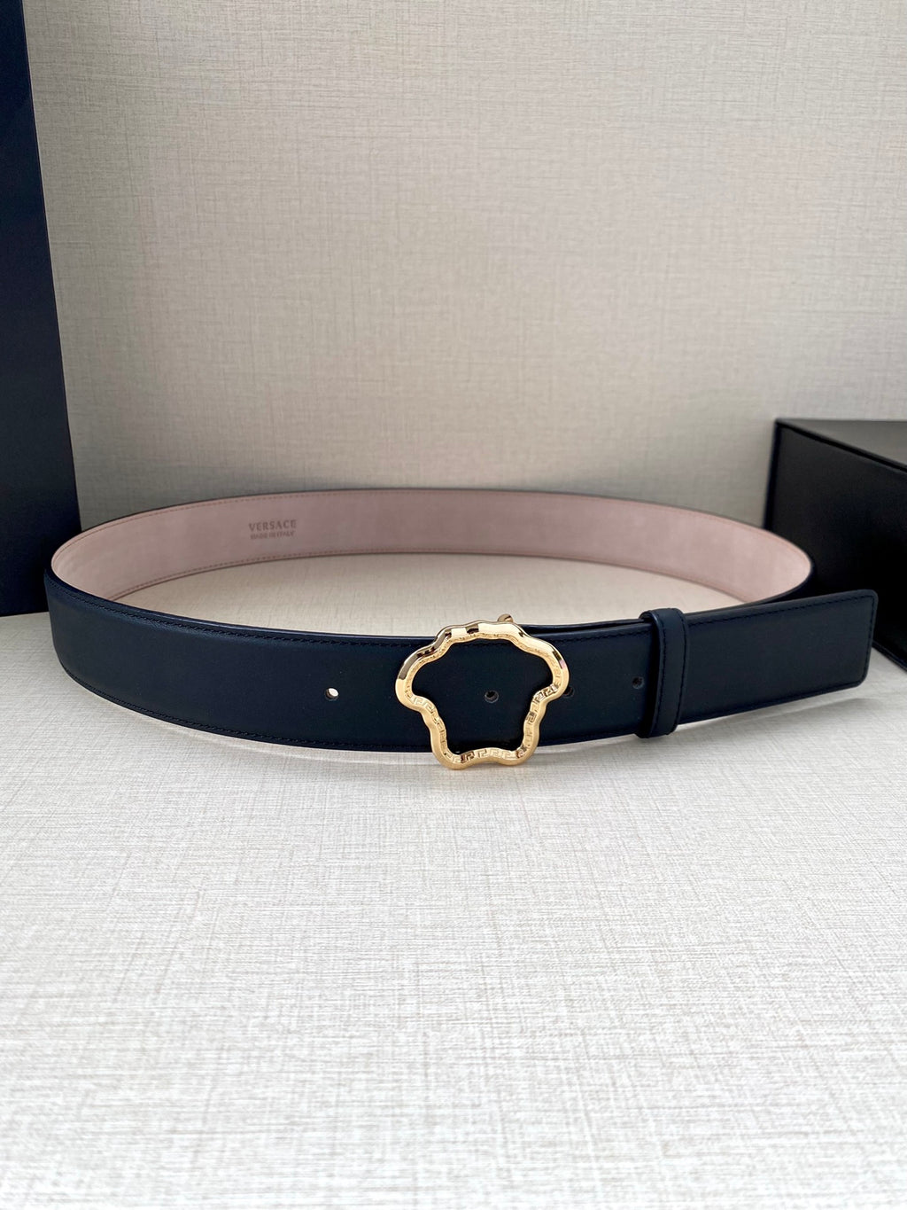 Navy leather belt with gold-tone logo buckle and light pink lining