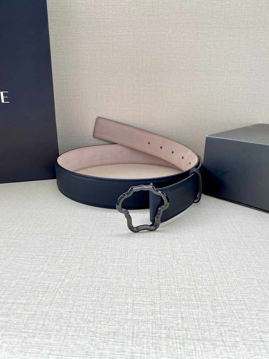 Dark blue leather belt with logo buckle and light pink underside