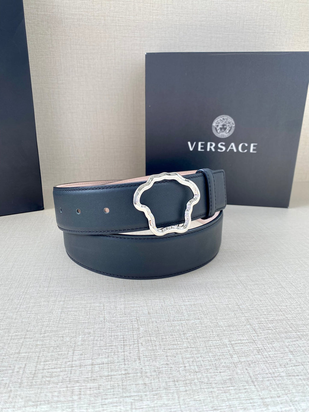 Dark blue leather belt with silver-tone logo buckle on display