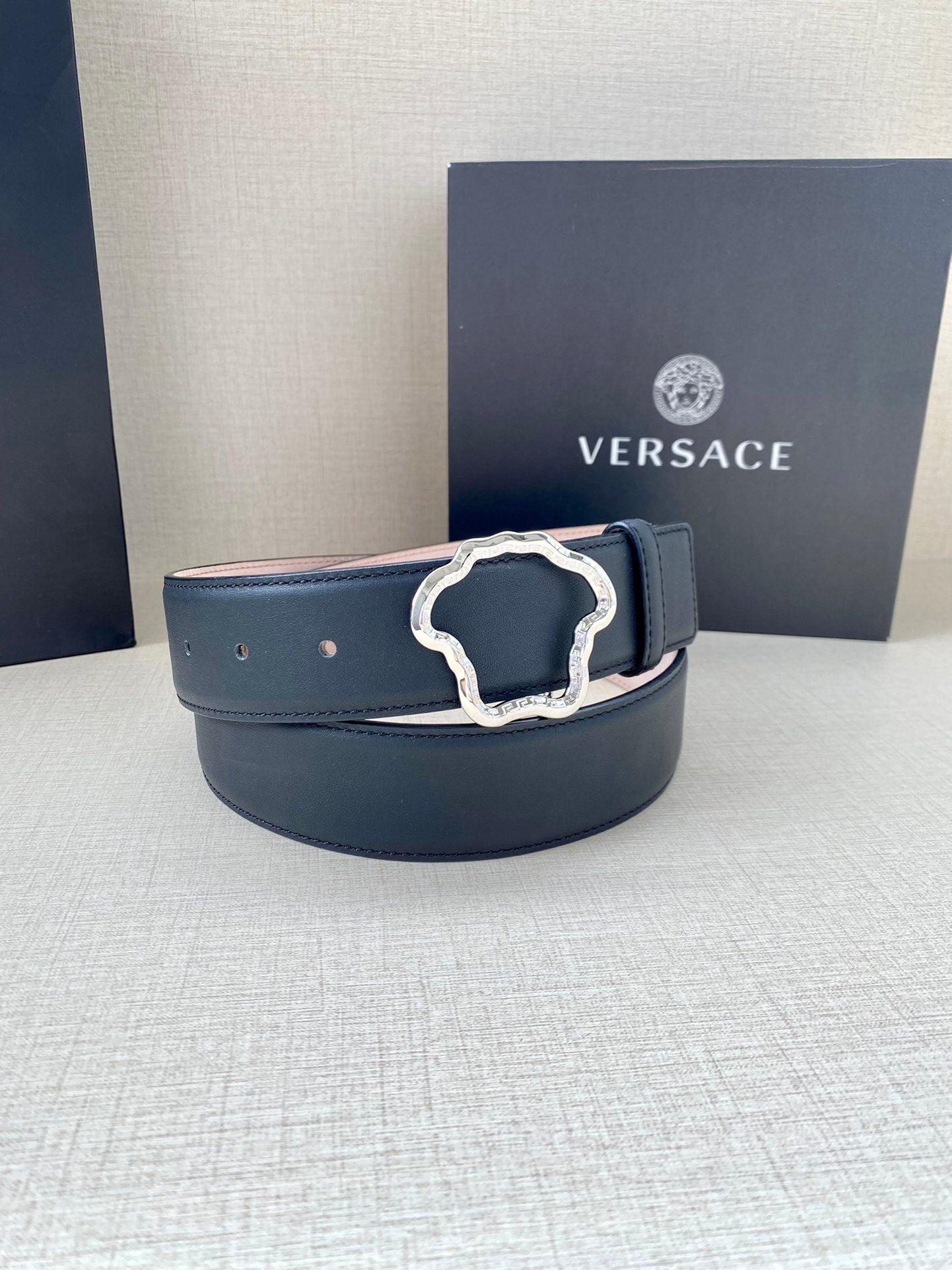 Dark blue leather belt with silver-tone logo buckle on display