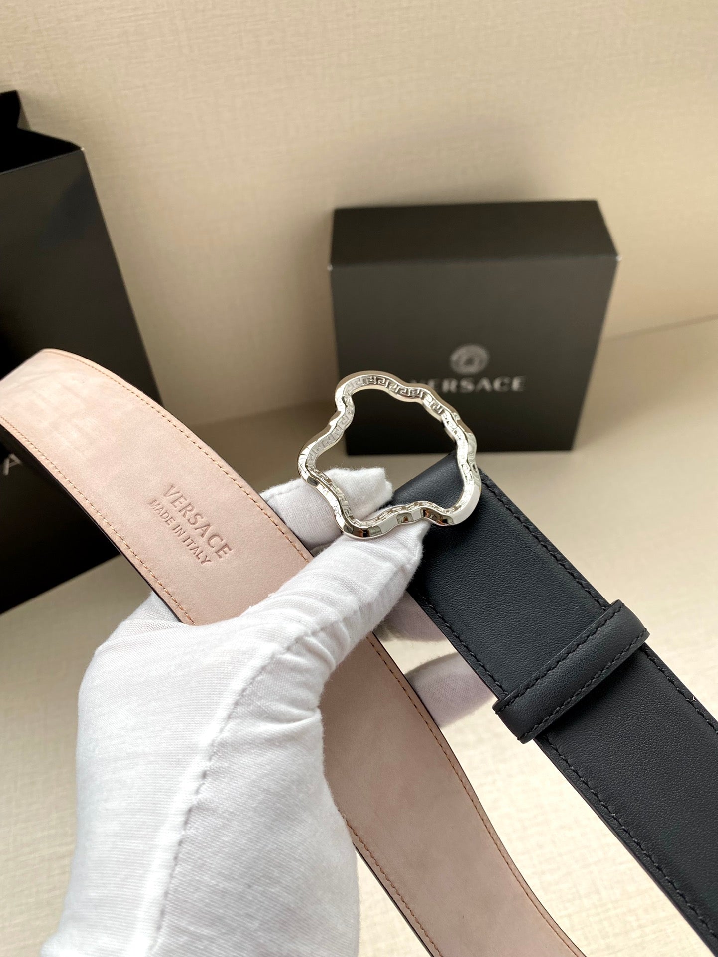 Dark blue leather belt with silver-tone logo buckle and pale pink strap