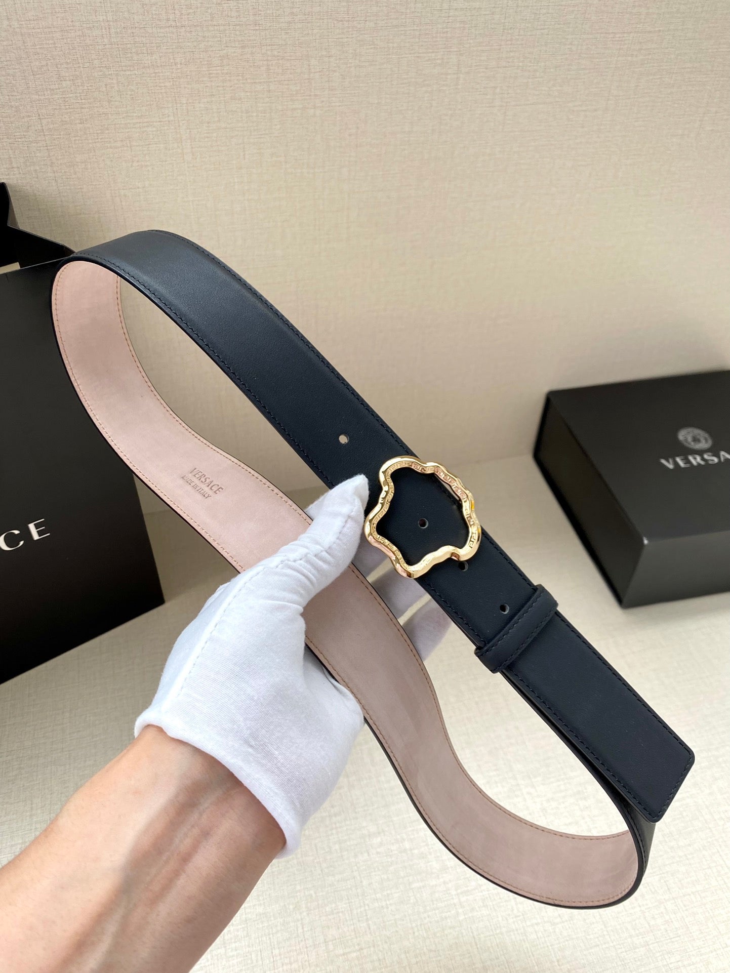 Dark blue leather belt with gold-tone ornate logo buckle