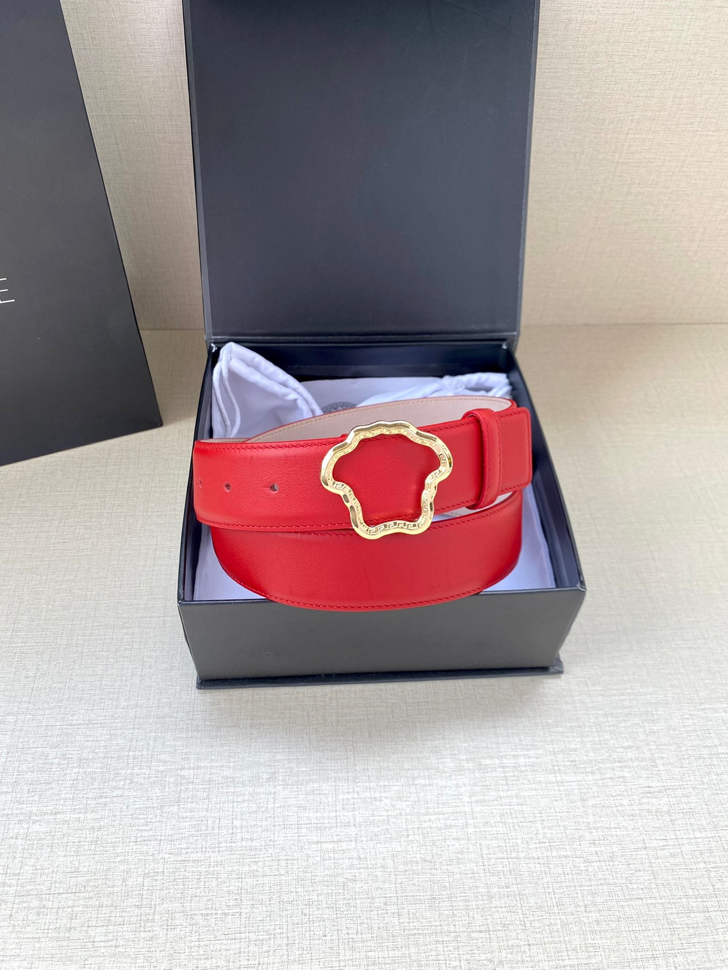 Red leather belt with gold Medusa-style buckle and adjustable punched holes