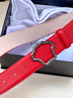 Red leather belt with silver Medusa-style buckle, close-up with punched holes