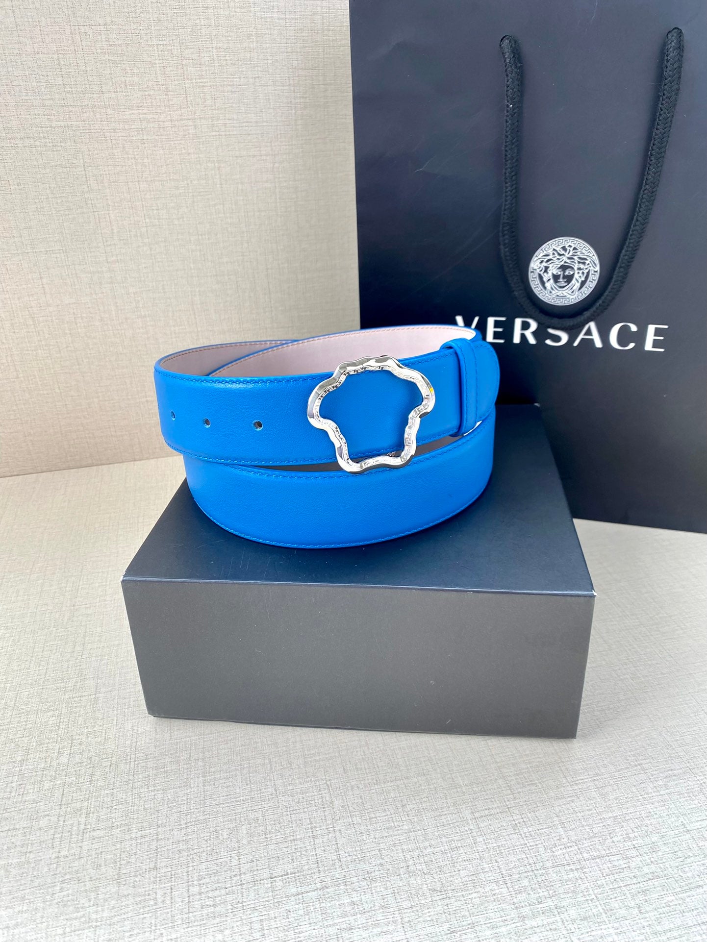 Versace belt in bright blue leather with decorative metal buckle on a box