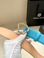 Blue leather belt with gold-toned ornate buckle over tan lining; stitched edges.