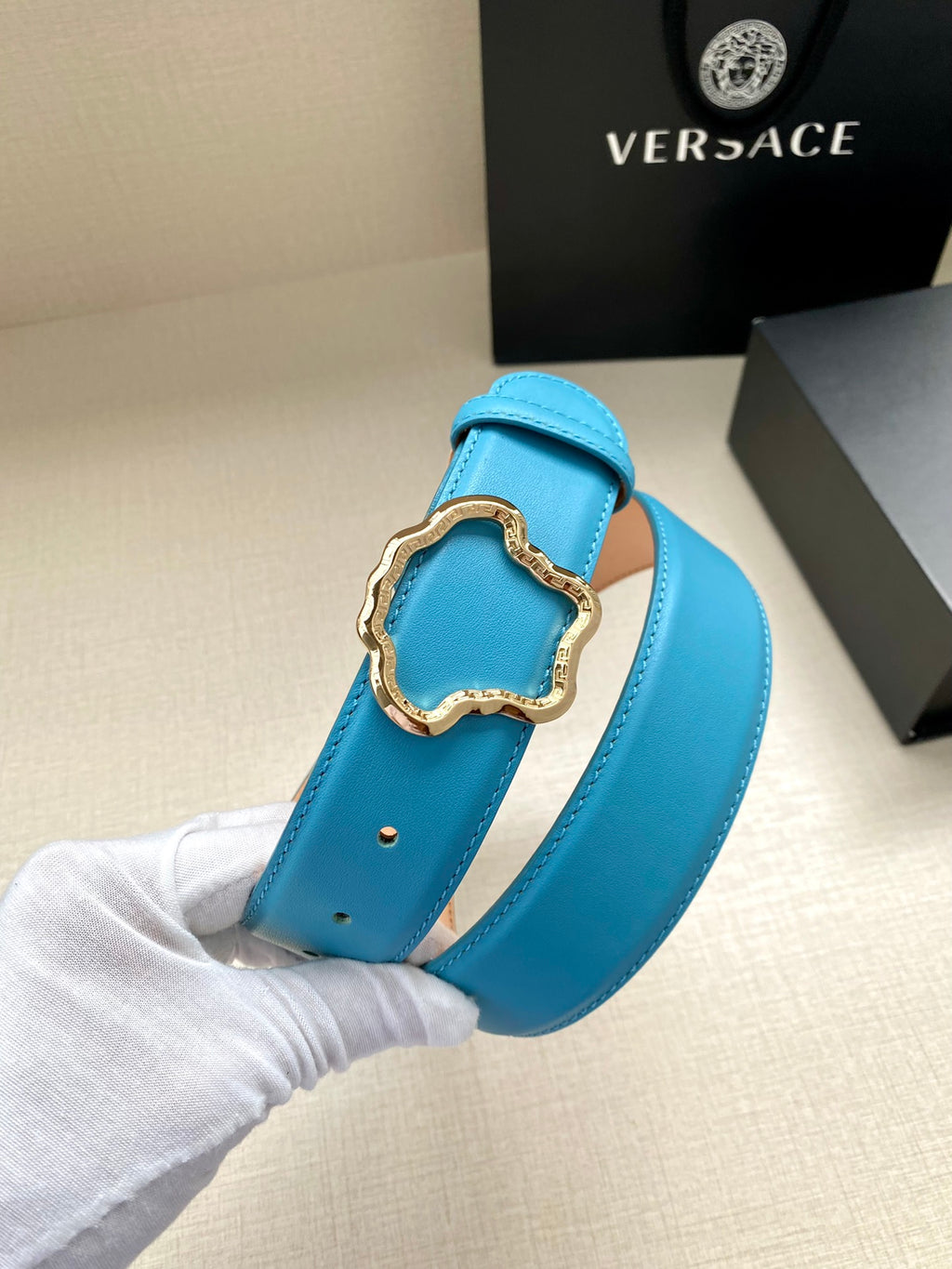 Blue leather belt with gold-toned ornate buckle clasp and smooth strap.