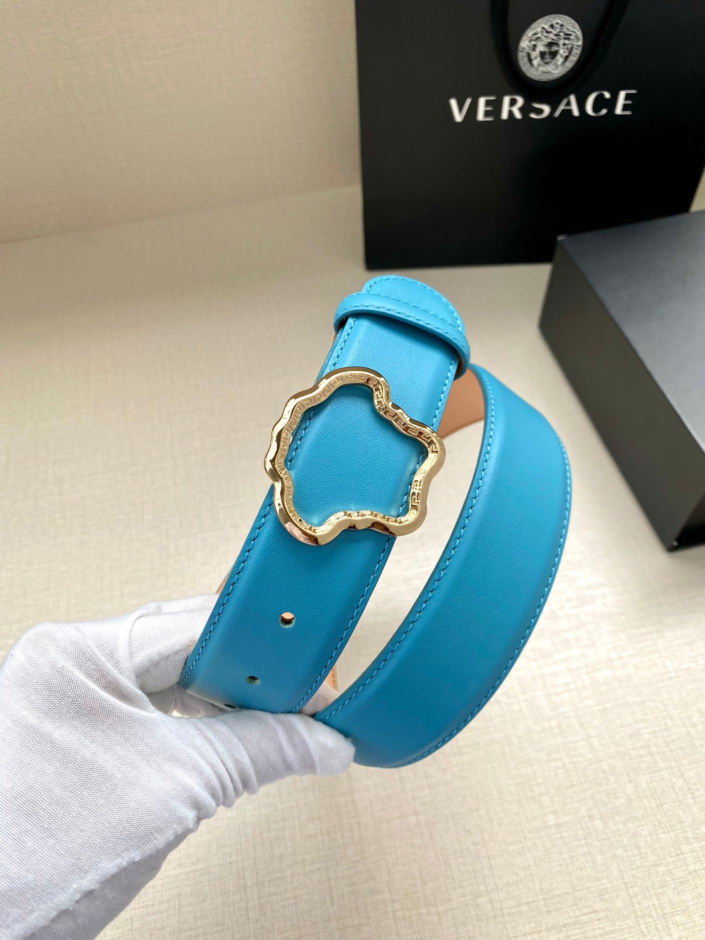 Blue leather belt with gold-toned ornate buckle clasp and smooth strap.
