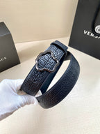 Versace belt close-up, dark navy logo texture and rectangular buckle with gold-tone accents.