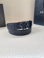 Versace belt rolled on display, dark navy logo pattern strap with silver-toned buckle detail.