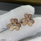 Gold floral stud earrings with clear pavé stones on white fabric.