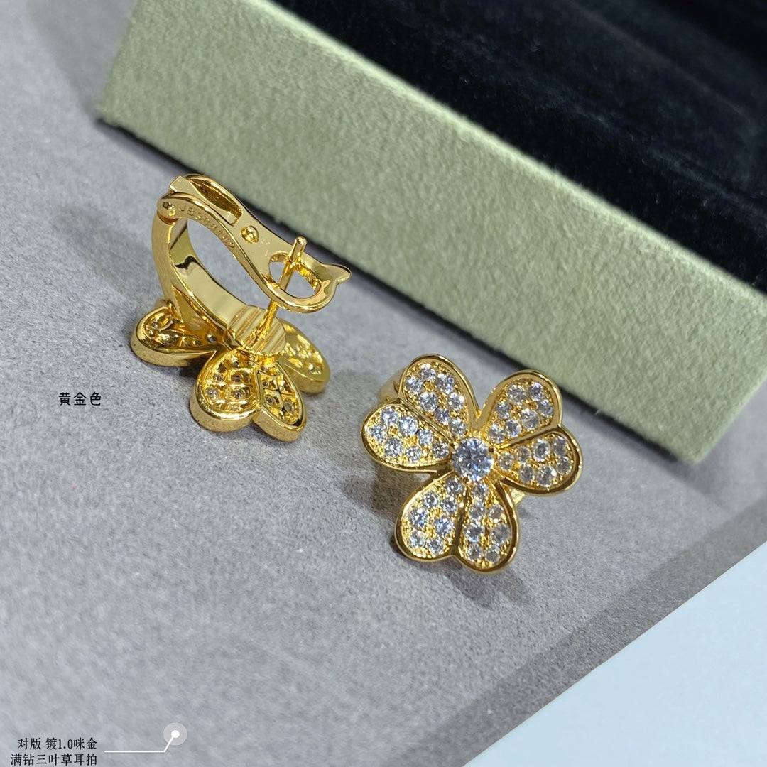 Gold hoop earrings with dangling charm and gold floral stud earrings.