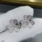 Silver floral stud earrings with clear pavé stones on white fabric.