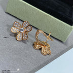 Gold floral stud earrings paired with gold hoop earrings with dangling charm.