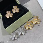 Gold floral stud earrings with heart-shaped petals and clear pavé stones.