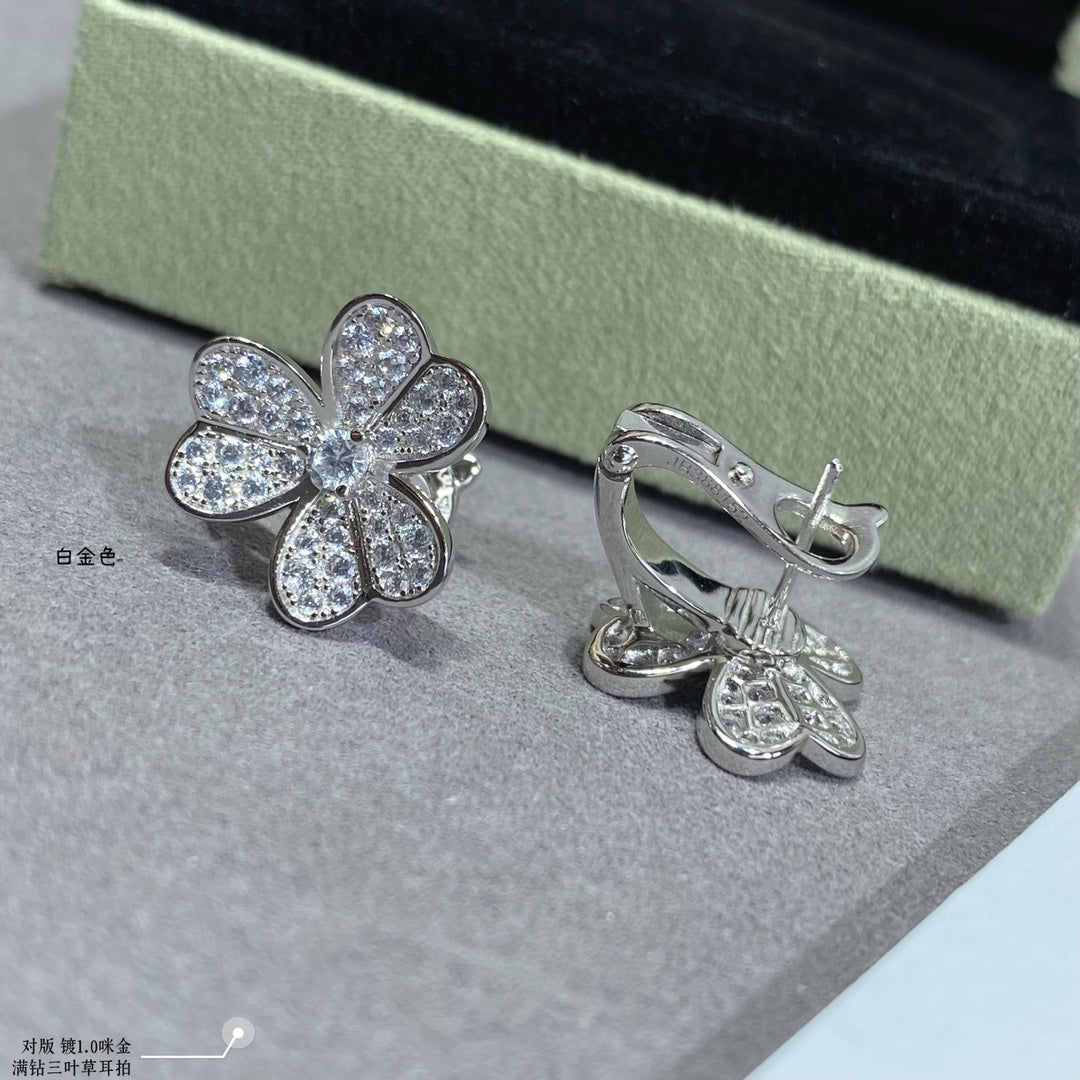 Silver floral stud earrings paired with silver hoop earrings with dangling charm.