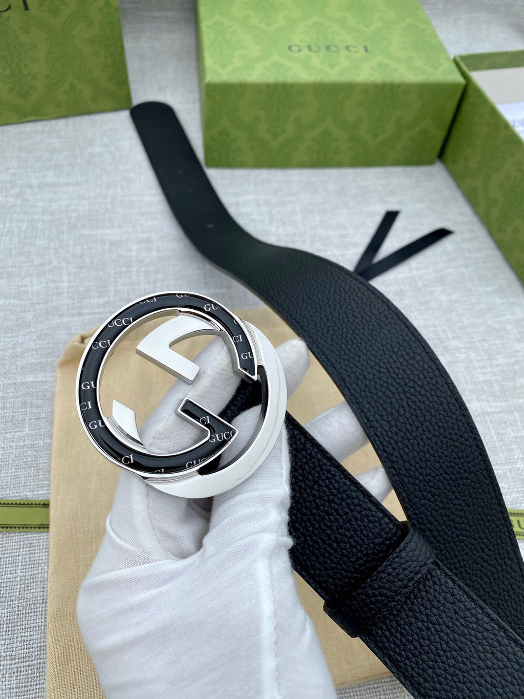 Black leather belt with silver-tone buckle and double G emblem, shown with box insert.
