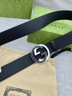Black leather belt with silver-tone double G buckle on a curved strap close-up.