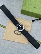 Black leather belt with silver-tone circular buckle featuring double G emblem.