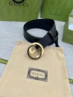 Black leather belt with gold-tone double G buckle, adjustable strap and metal ring.