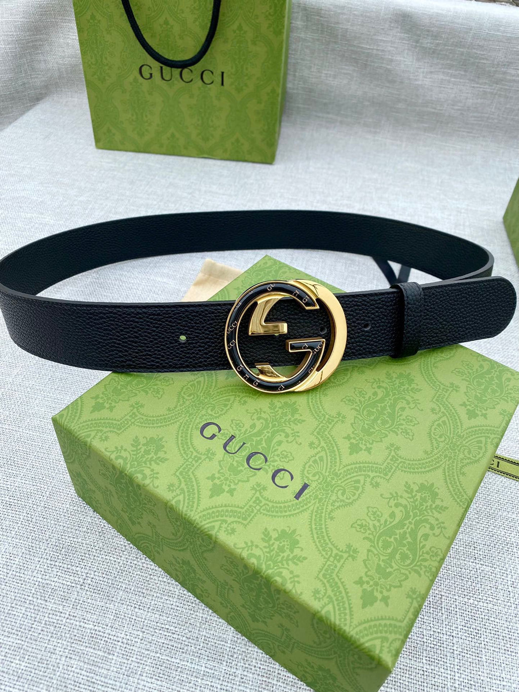 Black leather belt with gold-tone double G buckle and round center emblem.