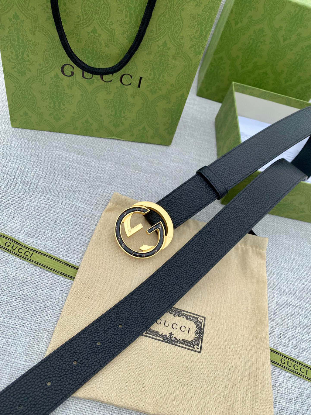 Black leather belt with gold-tone double G buckle on a long, flat strap.