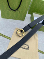 Black leather belt with gold-tone double G buckle on a long, flat strap.