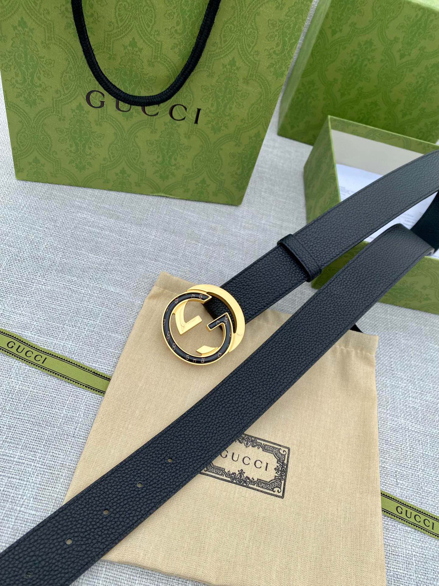 Black leather belt with gold-tone double G buckle on a long, flat strap.