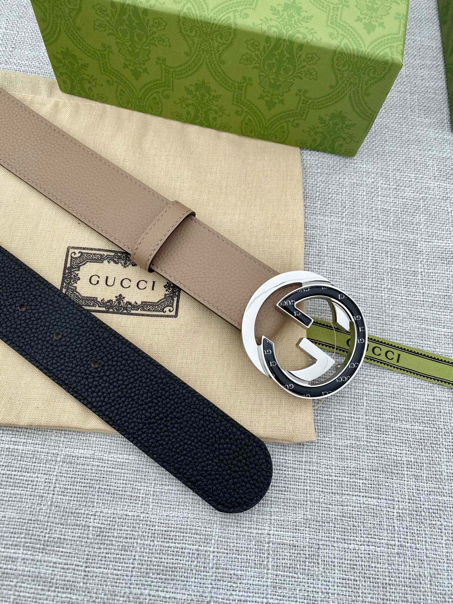 Beige leather belt with round GG-logo buckle, with dark navy belt beside