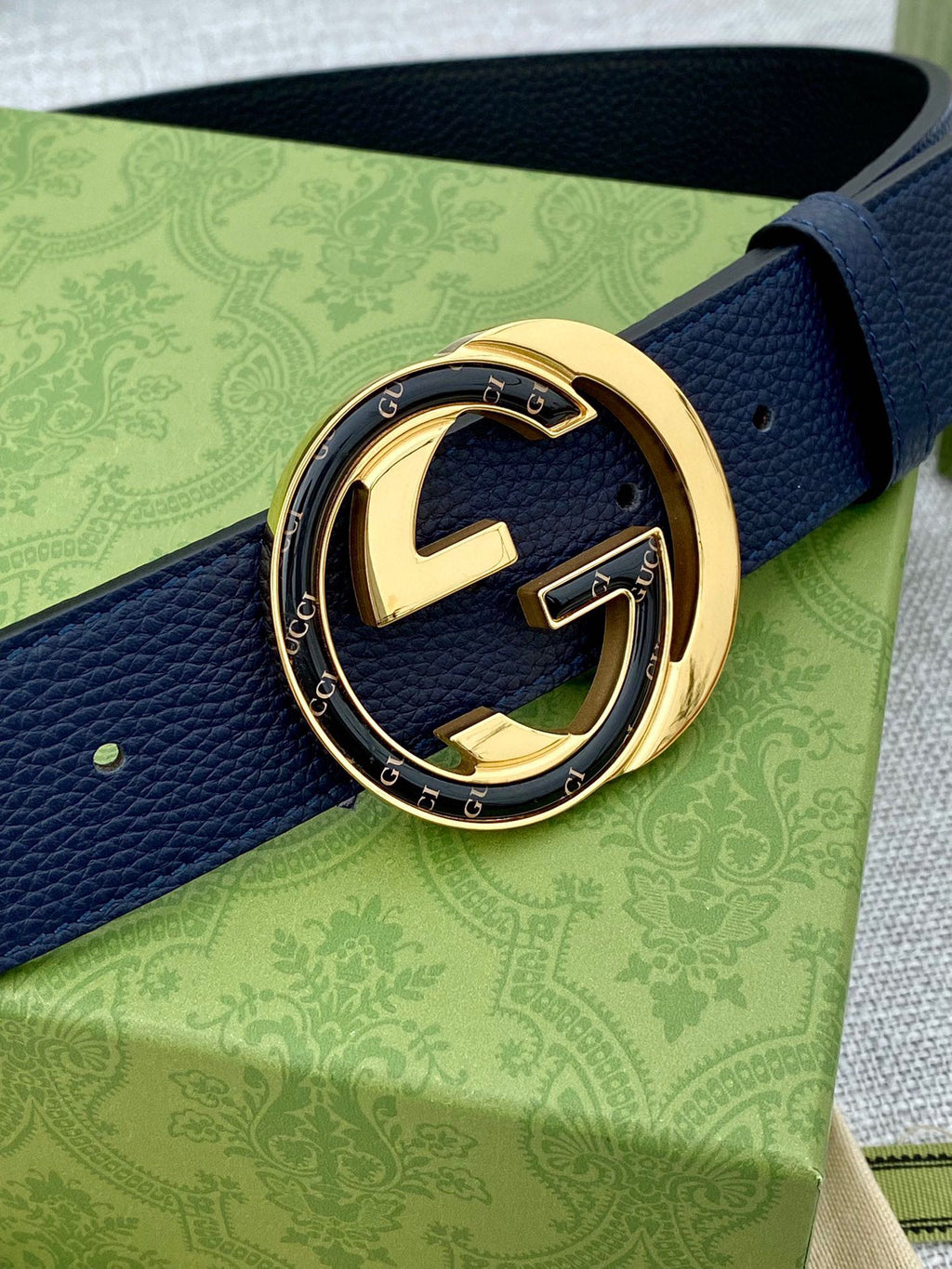 Navy leather belt with blue-and-gold GG logo buckle close-up