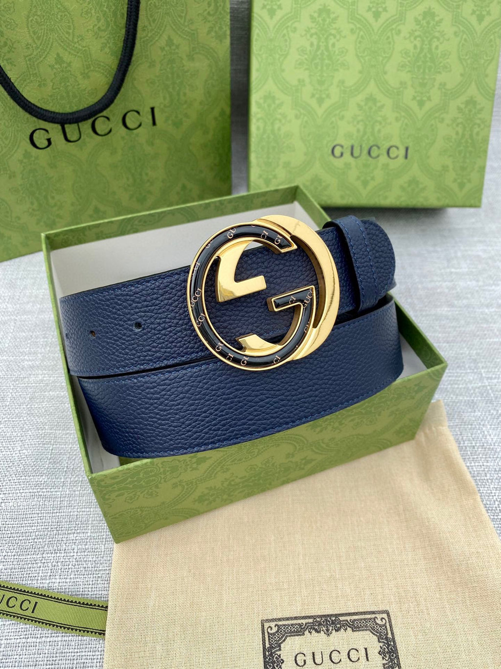 Navy leather belt with circular gold-tone GG logo buckle