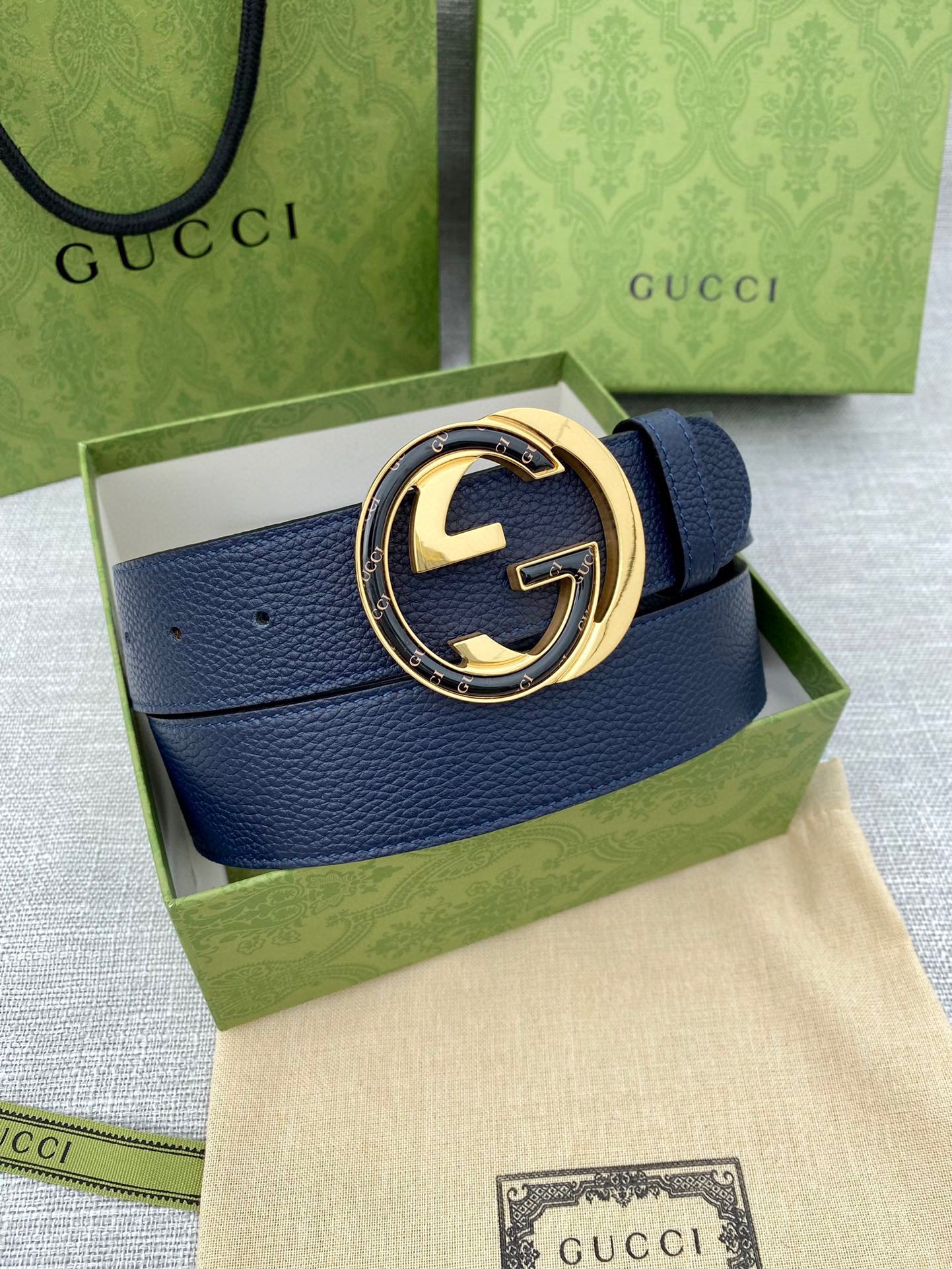 Navy leather belt with circular gold-tone GG logo buckle