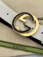 Gucci belt buckle close-up with gold-toned G motif on cream leather strap