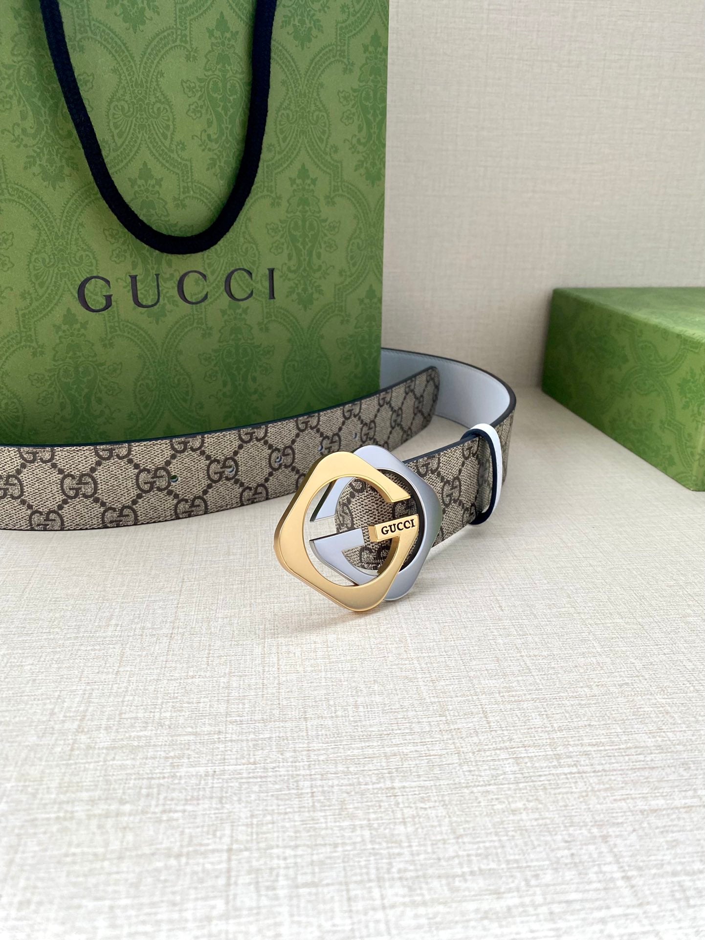 Gucci belt shown with round interlocking G buckle on beige-brown GG canvas strap and white edge
