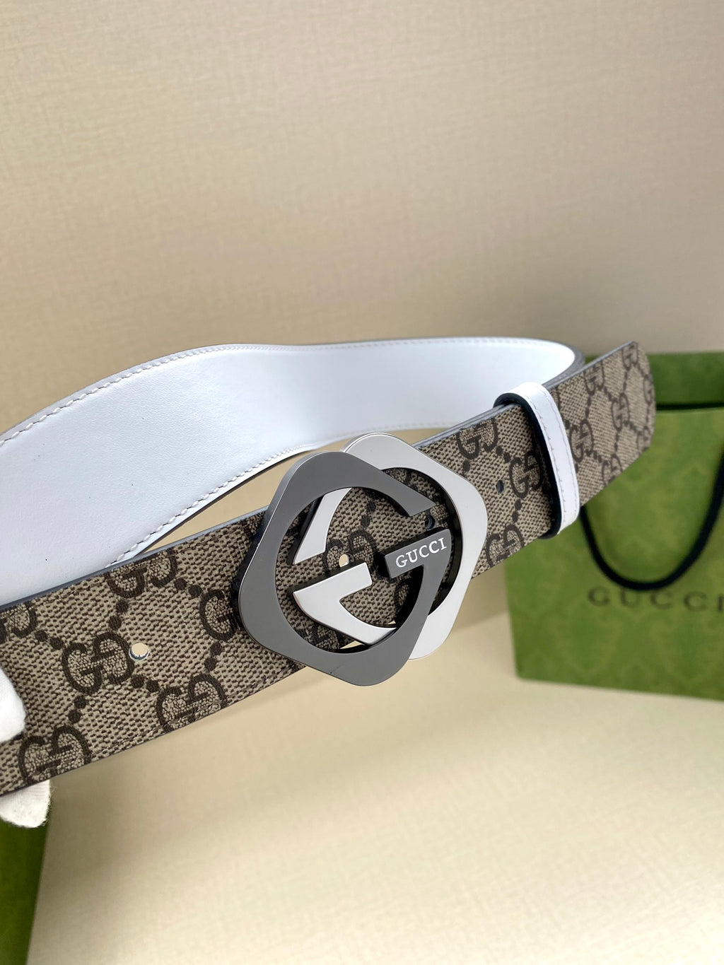 Gucci belt close-up: beige-brown GG canvas strap with white leather edge and round interlocking G buckle