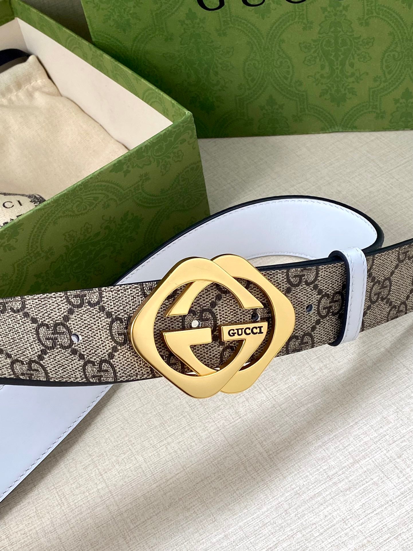 Gucci belt featuring GG monogram canvas and gold-tone Interlocking G buckle on white strap