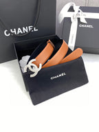 Tan leather belt with gold-tone CC buckle, displayed in a black gift box