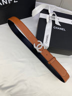 Tan leather belt with gold-tone CC buckle, laid across a navy fabric surface