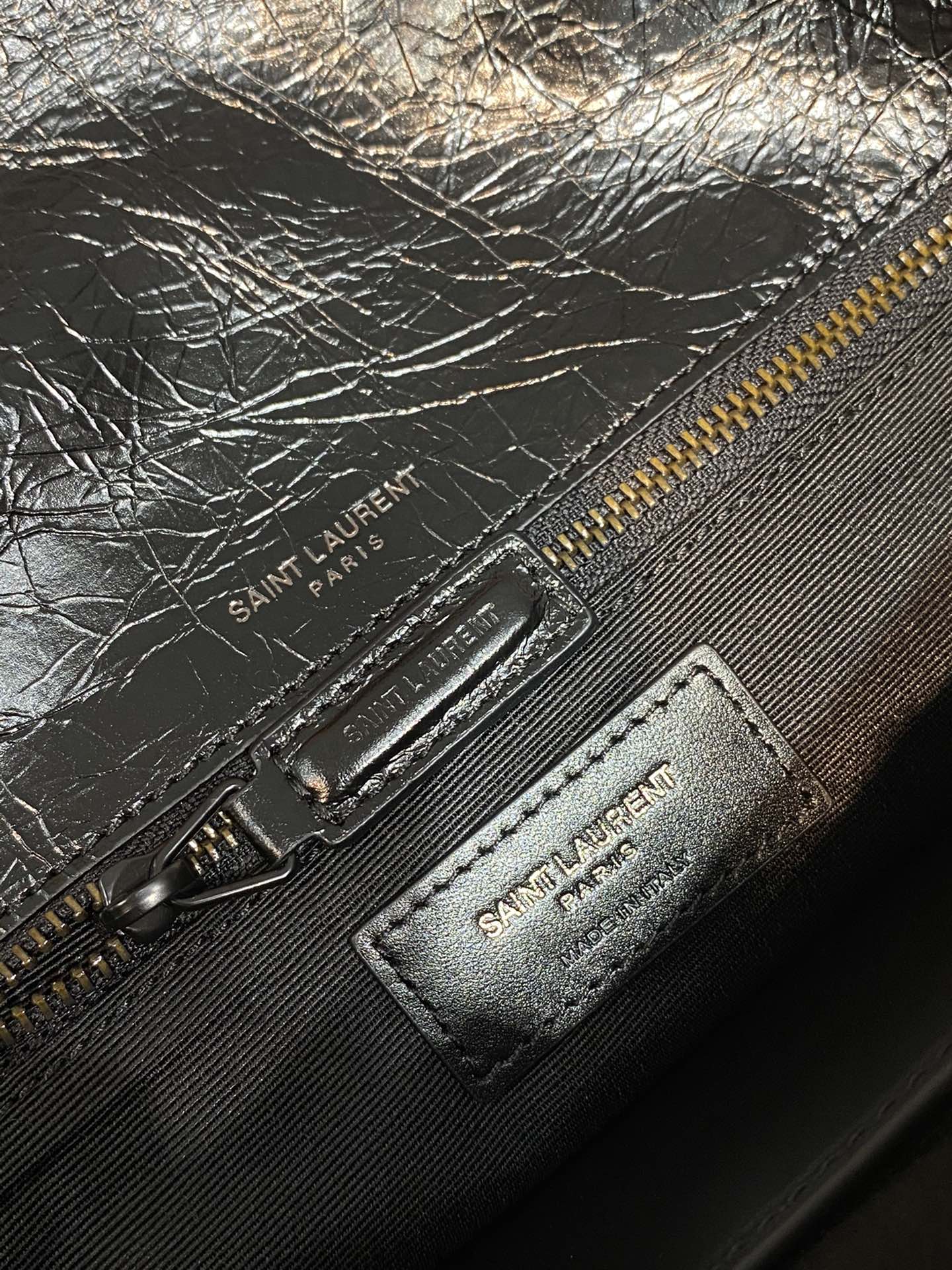 YSL Saint Laurent zipper pouch with embossed logo patch and metal pull on dark leather