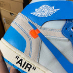 Blue high-top sneaker ankle area with embroidered wings and orange stripe detail.