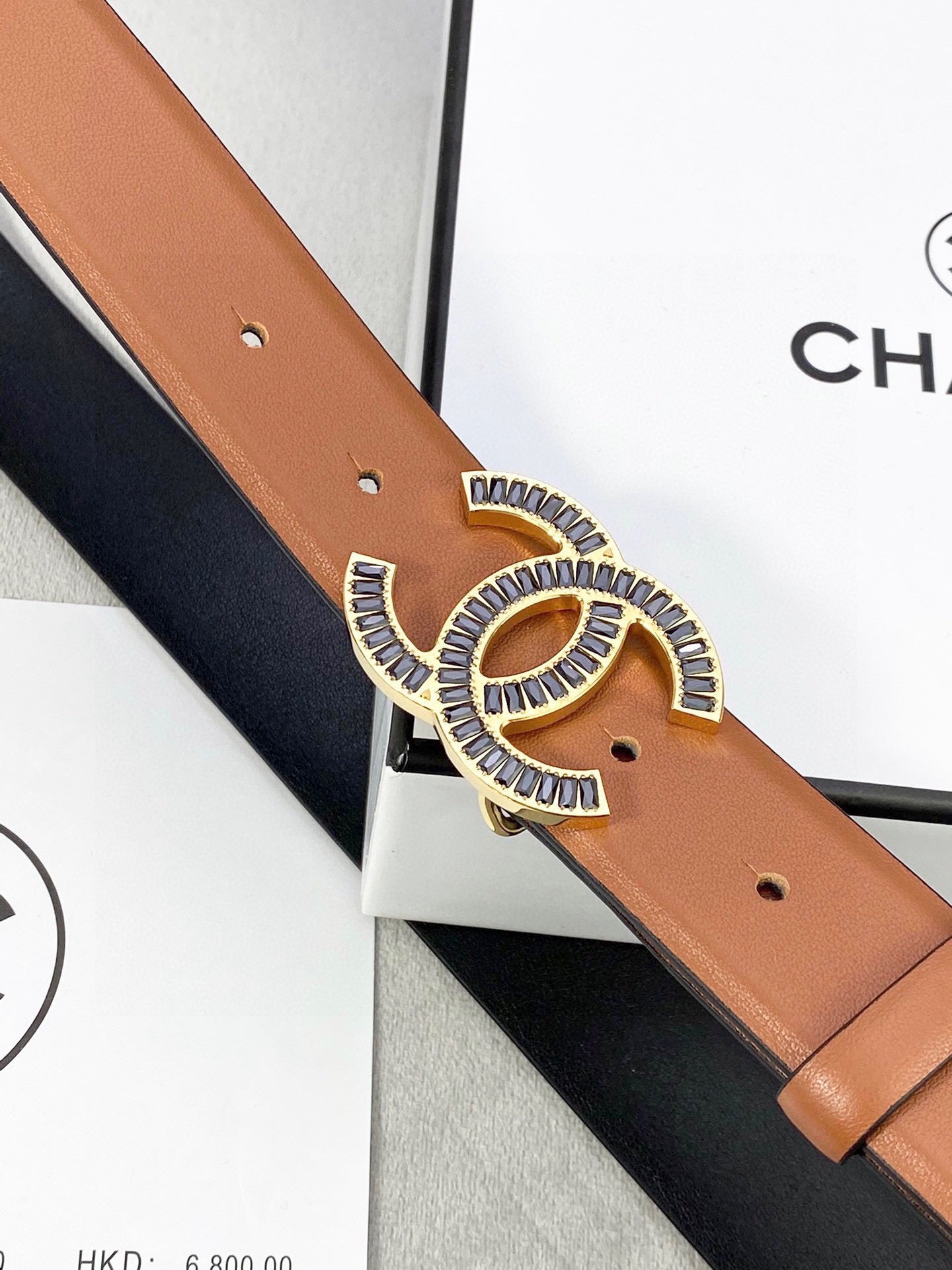 Chanel leather belt close-up with gold-tone interlocking CC buckle on tan strap