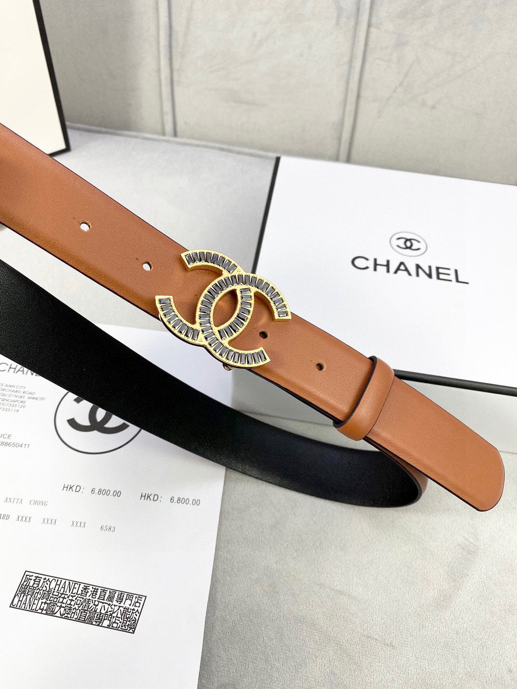 Chanel leather belt with tan strap and gold-tone CC buckle over black underside