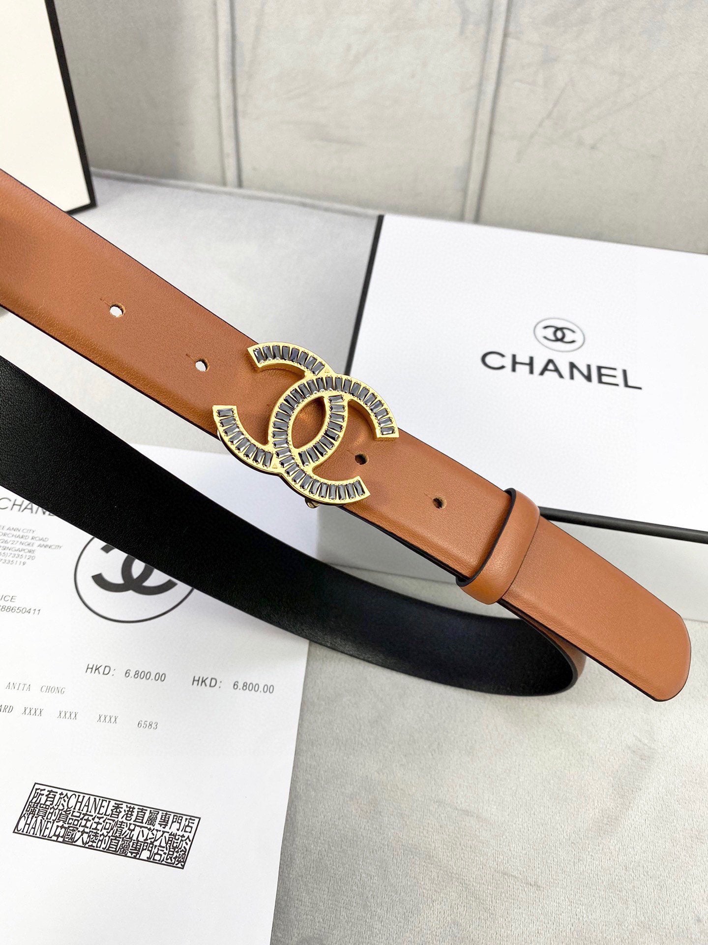 Chanel leather belt with tan strap and gold-tone CC buckle over black underside