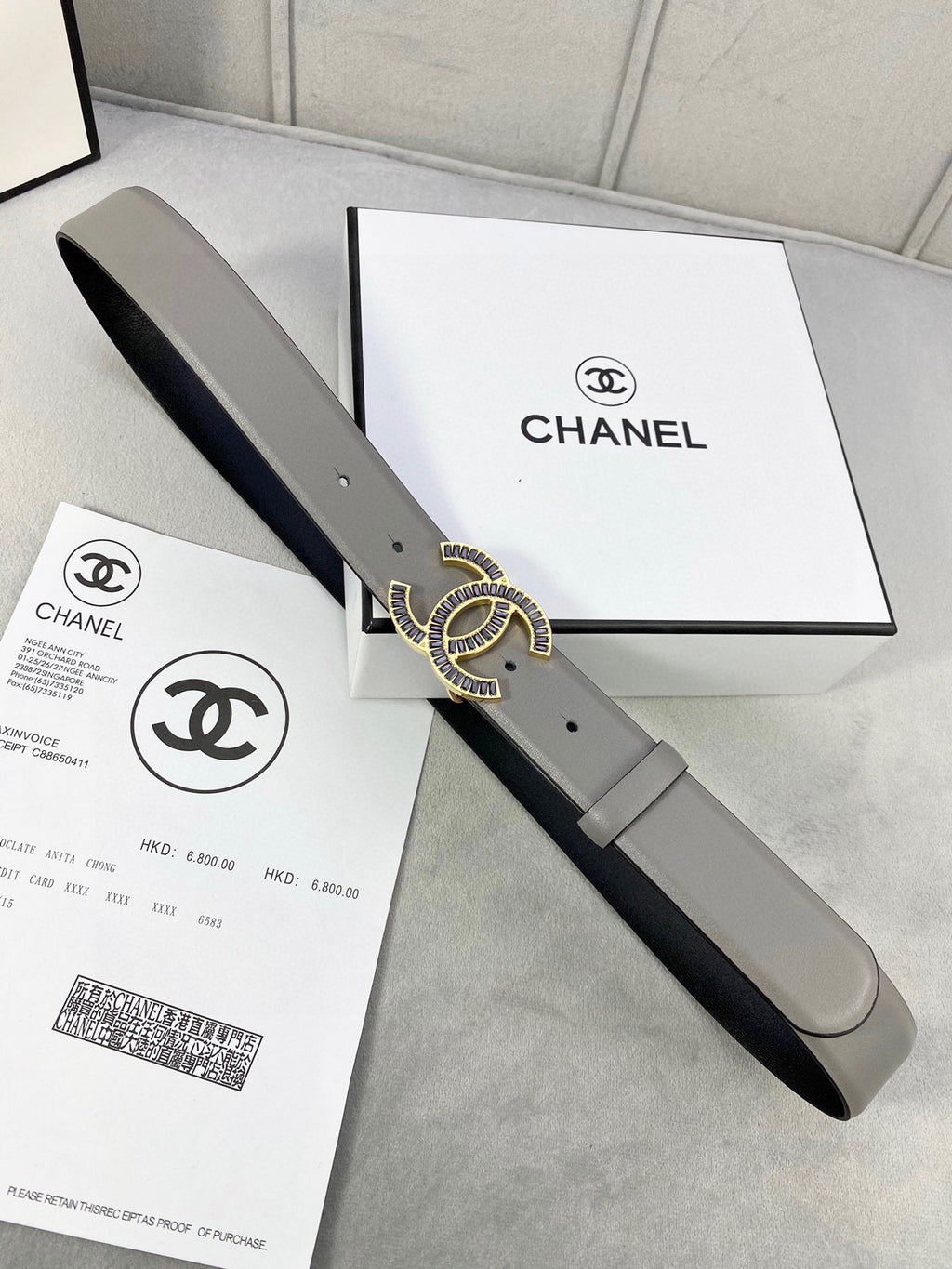 Chanel leather belt with gray strap, black underside, and gold-tone CC logo buckle