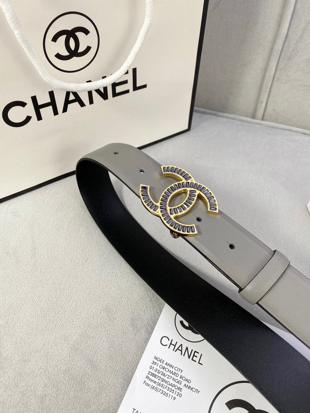 Chanel leather belt close-up with gray strap, black underside, and gold-tone CC buckle