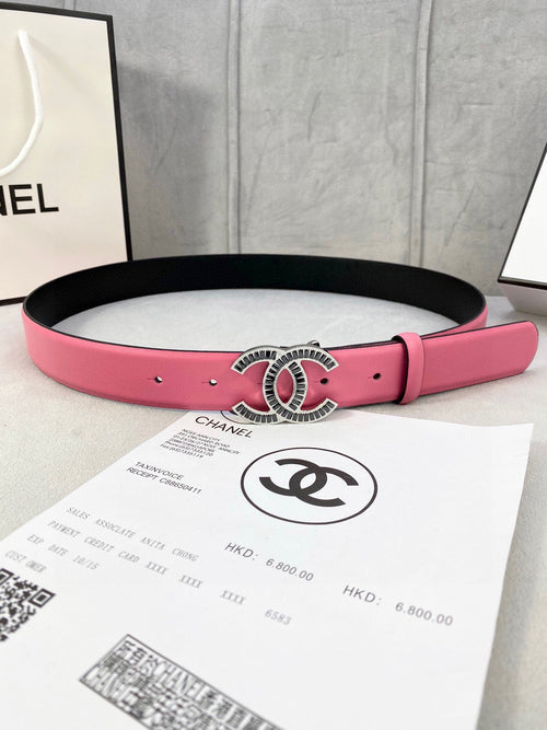 Chanel belt with pink leather strap and ornate oval CC buckle on black backing.